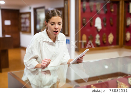 Young girl in the museum looks at the exposition behind glass case 78882551