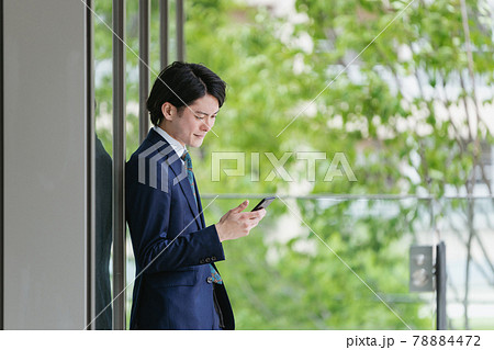 スマートフォンを見る若い男性・ビジネスマンが出社してIoTをするイメージ スマートフォンを見る若い男性・ビジネスマンが出社してIoTをするイメージ 78884472