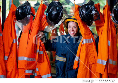 Fireman or firefighter woman stand and break into fireman suit on hanger and smile with happy Fireman or firefighter woman stand and break into fireman suit on hanger and smile with happy 78885537
