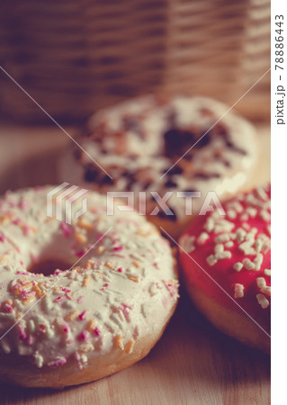 White, pink and brown glazed donuts on wooden background and near rattan basket . 78886443