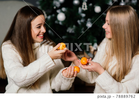 Girlfriends celebrating New year eve and Christmas and eating mandarins. Gifts, decorated fir. Girlfriends celebrating New year eve and Christmas and eating mandarins. Gifts, decorated fir. 78889762