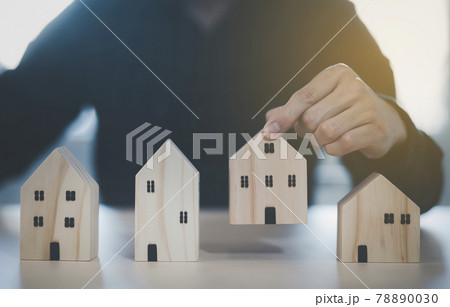 Man hand choosing mini wood house model from model on wood table, Planning buy Real Estate, Planning to buy property. concept of Choose the best. 78890030