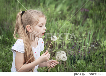 Little girl with white dandelions in her hands 78891029