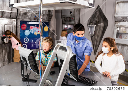 Enthusiastic children in protective masks play in the quest room of inscrutable bunker Enthusiastic children in protective masks play in the quest room of inscrutable bunker 78892676