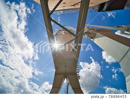 White cargo crane in the harbour, photographed from below in the direction of the sun through the supports, abstract impression, industry 78896455