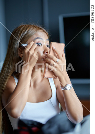 Beautiful young Asian woman doing evening make-up Beautiful young Asian woman doing evening make-up 78896522