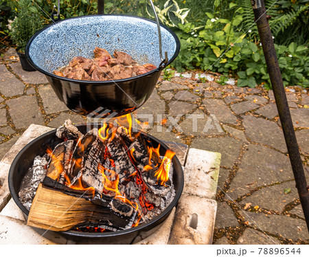 Frying the beef in a cauldron over an open wood fire to prepare the Hungarian cauldron goulash, food 78896544