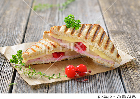 Pressed and toasted sandwich Hawaiian style with ham, pineapple and cheese served on sandwich paper 78897296