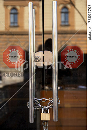 Closed Store due to Coronavirus pandemic. Locked Store Door with Padlock and Chains and Covid 19 sign 78897708