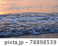 夕日に照らされた海と浜辺に寄る波 78898539