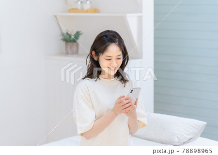 ベッドでスマホを使う若い女性 78898965