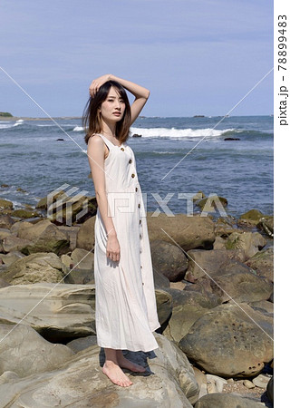 晴れた日の海岸でポーズをとるワンピース姿の若い女性 晴れた日の海岸でポーズをとるワンピース姿の若い女性 78899483