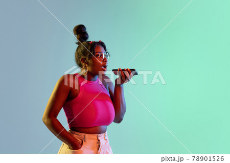Young beautiful happy African girl isolated on blue-green background in neon. 78901526