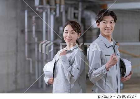 工事現場でヘルメットを持って立つ作業員2人のポートレート 78903527