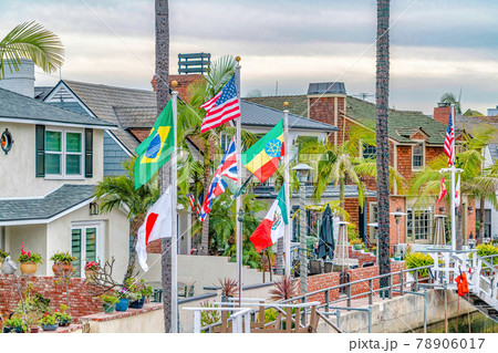 Waterfront houses colorful flags and palm trees along a canal under cloudy sky Waterfront houses colorful flags and palm trees along a canal under cloudy sky 78906017