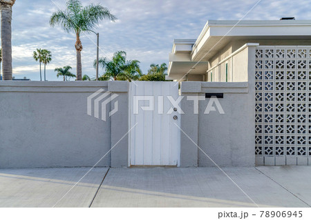White gate and concrete fence agaonst trees and cloudy sky of beautiful home White gate and concrete fence agaonst trees and cloudy sky of beautiful home 78906945