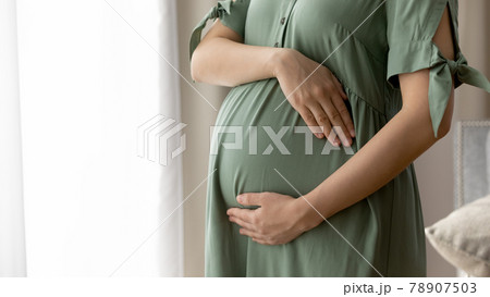Close up cropped of pregnant woman in dress embracing belly Close up cropped of pregnant woman in dress embracing belly 78907503