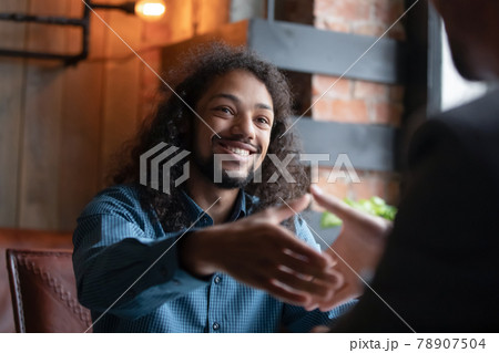Happy young mixed race guy shaking hands with agent. 78907504