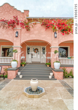 Home with pink exterior walls arches at the porch and front door with sidelights 78908795