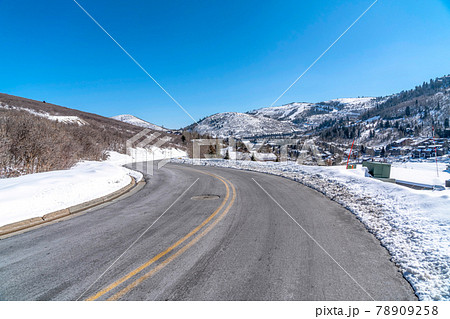 Road on a snowy setting curving through the mountain slopes in Park City Utah Road on a snowy setting curving through the mountain slopes in Park City Utah 78909258