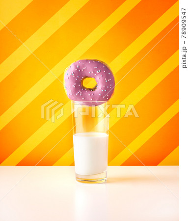 Purple doughnut with glass of milk on striped orange background 78909547