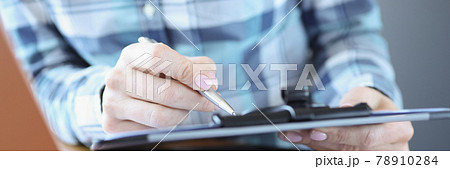 Manager sits at his desk and holds documents with pen 78910284