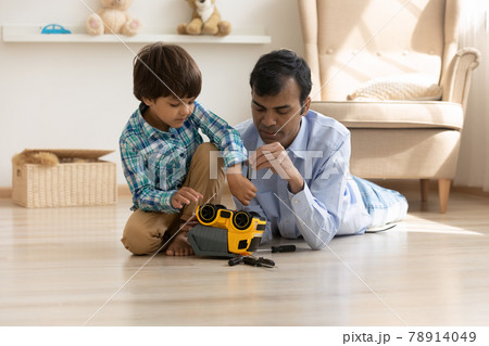 Indian father and small son repair toy car together Indian father and small son repair toy car together 78914049