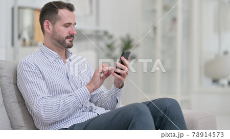 Attractive Young Man using Smartphone at Home  78914573