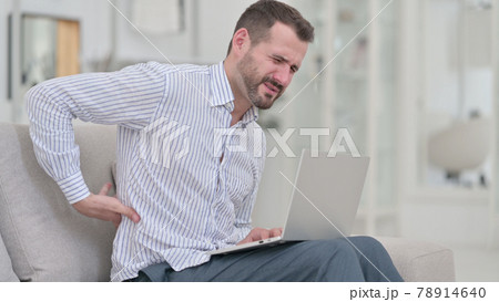 Young Man with Back Pain using Laptop at Home  78914640