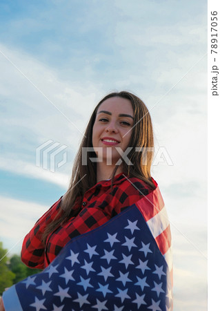 Young millennial brunette woman holding The National Flag of USA. American Flag. Tourist traveler or patriotism. Immigrant in free country. July 4th Independence Day. Caucasian 78917056