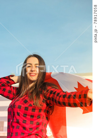 Young millennial brunette woman holding The National Flag of Canada. Canadian Flag or the Maple Leaf. Tourist traveler or patriotism. Immigrant in a free country. Independence day 1th july Young millennial brunette woman holding The National Flag of Canada. Canadian Flag or the Maple Leaf. Tourist traveler or patriotism. Immigrant in a free country. Independence day 1th july 78917058