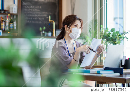 カフェ風オフィスでマスクをして仕事をする女性 78917542