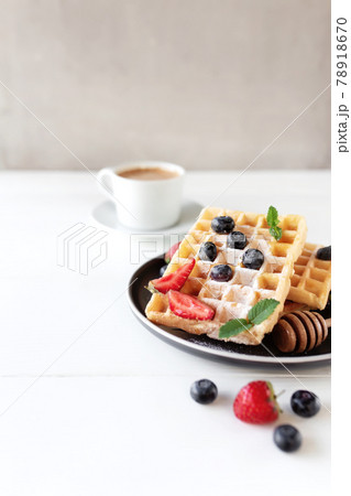 Waffles plate on table with blueberry, strawberry, mint and white cup of coffee 78918670