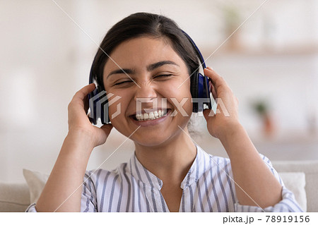 Smiling Indian woman listen to music in headphones 78919156