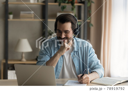 Happy young man listening educational online lecture on computer. Happy young man listening educational online lecture on computer. 78919792