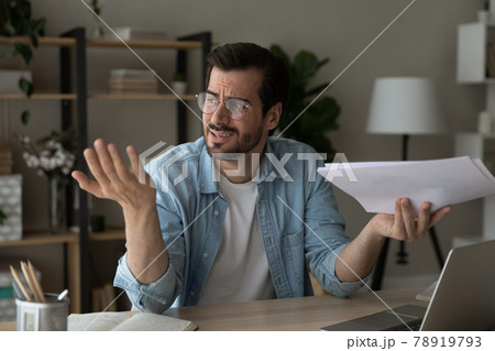 Frustrated young man feeling stressed of reading bad news. Frustrated young man feeling stressed of reading bad news. 78919793
