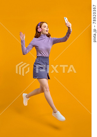 Excited Redhead Woman In Heaphones Jumping, Walking And Talking On Phone Excited Redhead Woman In Heaphones Jumping, Walking And Talking On Phone 78920367