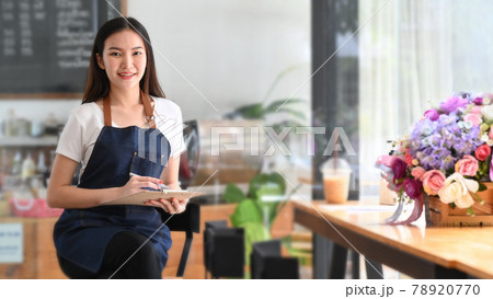 Female coffee shop owner holding note pad and smiling to camera. Female coffee shop owner holding note pad and smiling to camera. 78920770