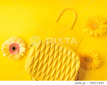Yellow fashion lady handbag with gerbera flowers on monochrome background with paper shopping bag Yellow fashion lady handbag with gerbera flowers on monochrome background with paper shopping bag 78921991