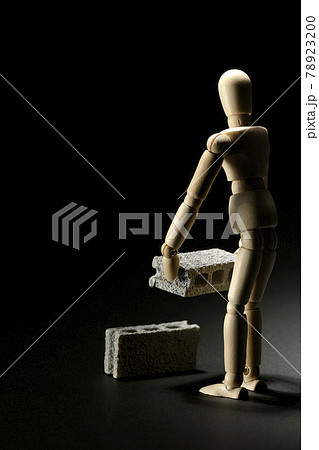 コンクリートブロックを運ぶデッサン人形を黒背景で撮影の写真素材 7230