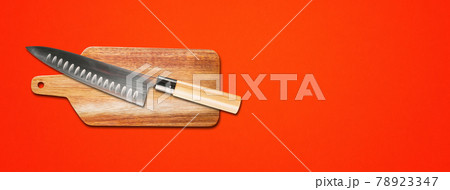 Traditional Japanese gyuto chief knife on a cutting board. Red banner background 78923347