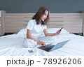 woman lying down the bed with laptop and phone 78926206