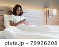 Young woman using smartphone on bed 78926208