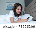 Young woman using smartphone on bed 78926209