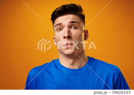 Portrait of crazy amazed young man in blue t-shirt against yellow background Portrait of crazy amazed young man in blue t-shirt against yellow background 78926235