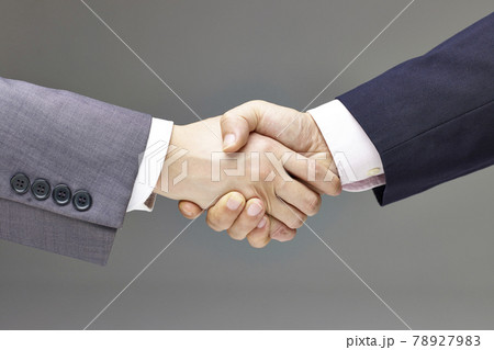 two businessmen in suit shaking hands, gray background. two businessmen in suit shaking hands, gray background. 78927983