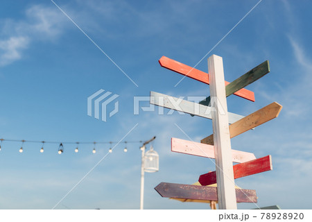 Guidepost with bright colored arrows in the sunlight with blue sky background. 78928920