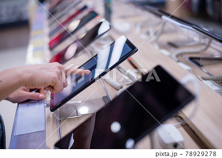 Faceless caucasian woman chooses a smartphone in an electronics store. Close-up of a female hand with a phone tester 78929278