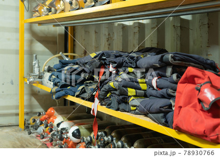 Firefighter or fireman safety protection tools, extinguisher, uniform in a gear storage room, an emergency accident rescue safety and security equipment 78930766