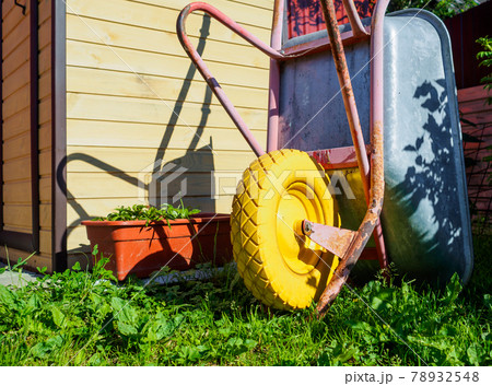 Garden cart with yellow wheel on green grass. 78932548